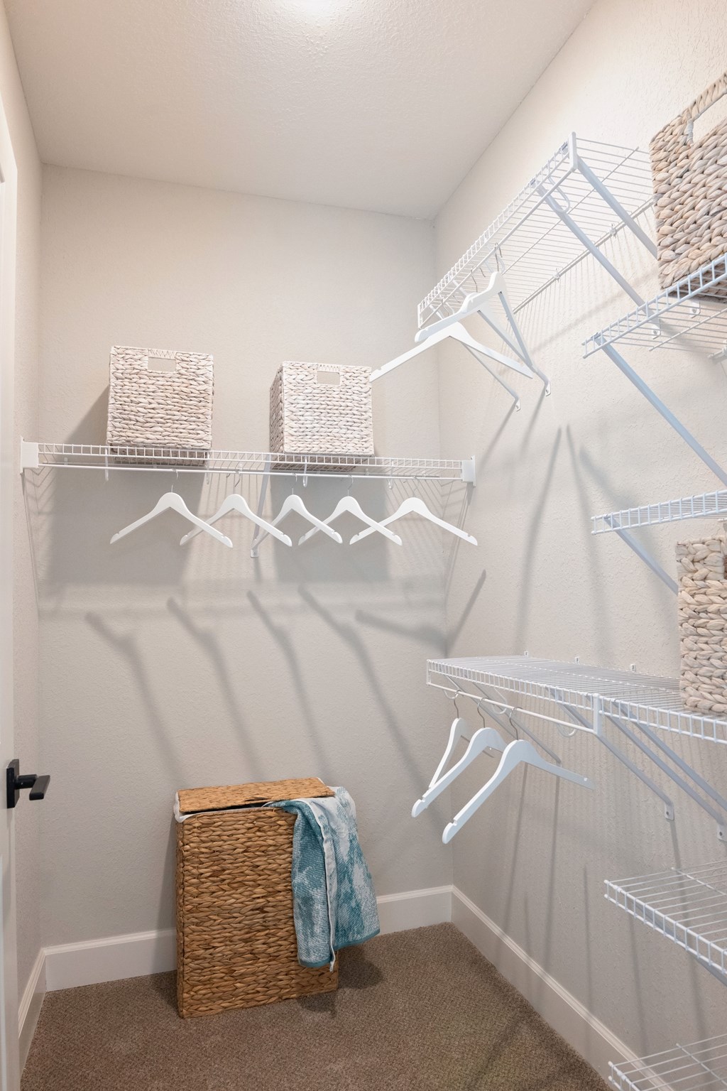 A white closet with a basket and a blue towel.