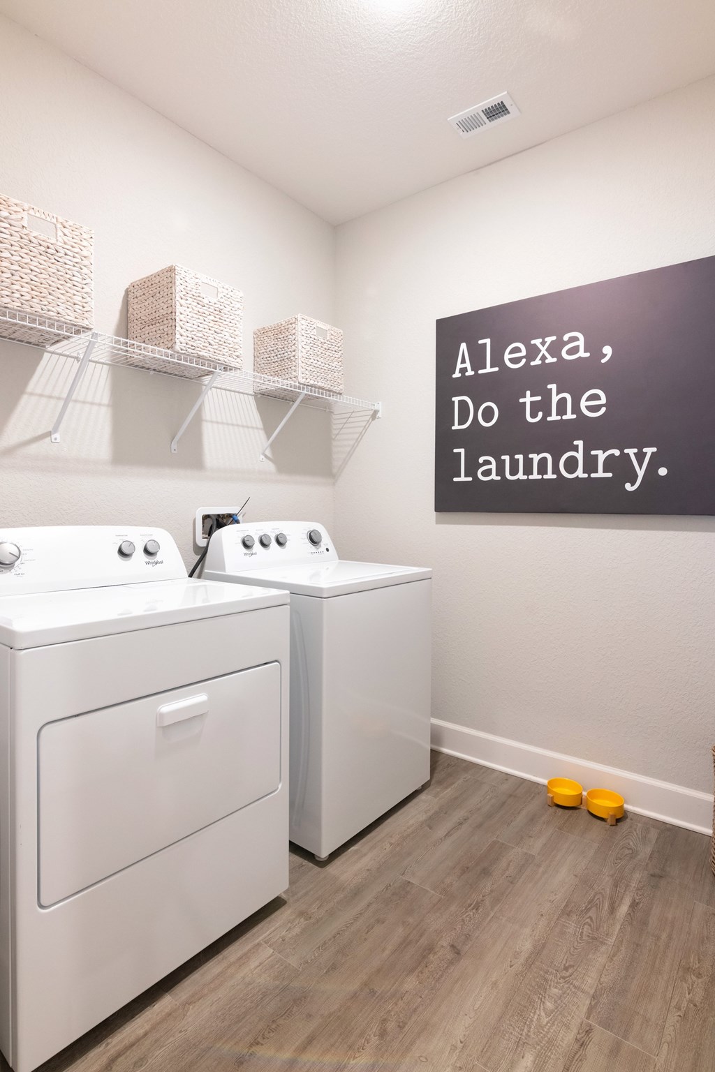 A laundry room with a sign that says "Alexa, do the laundry."