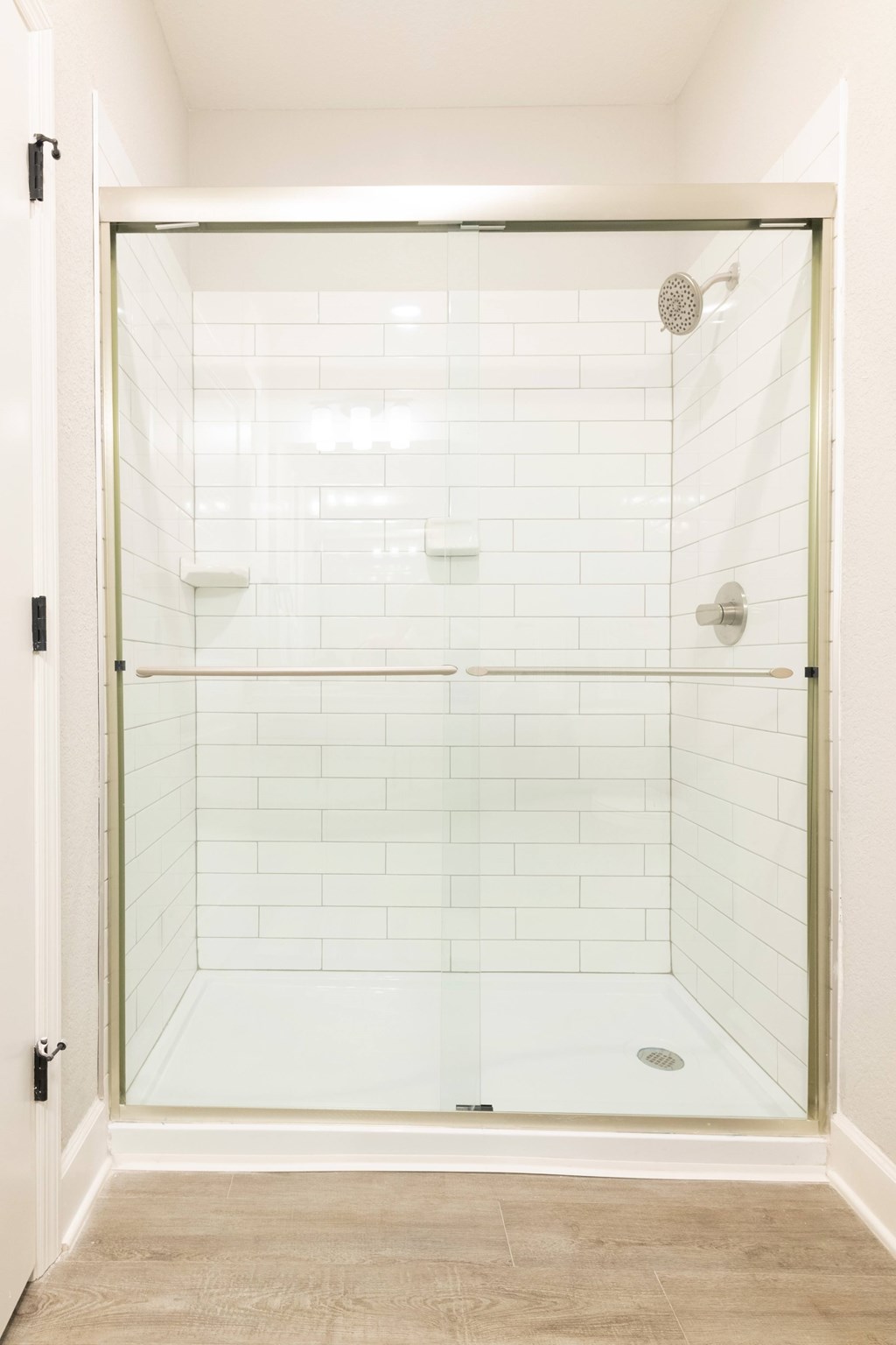 A white tiled shower with a glass door.