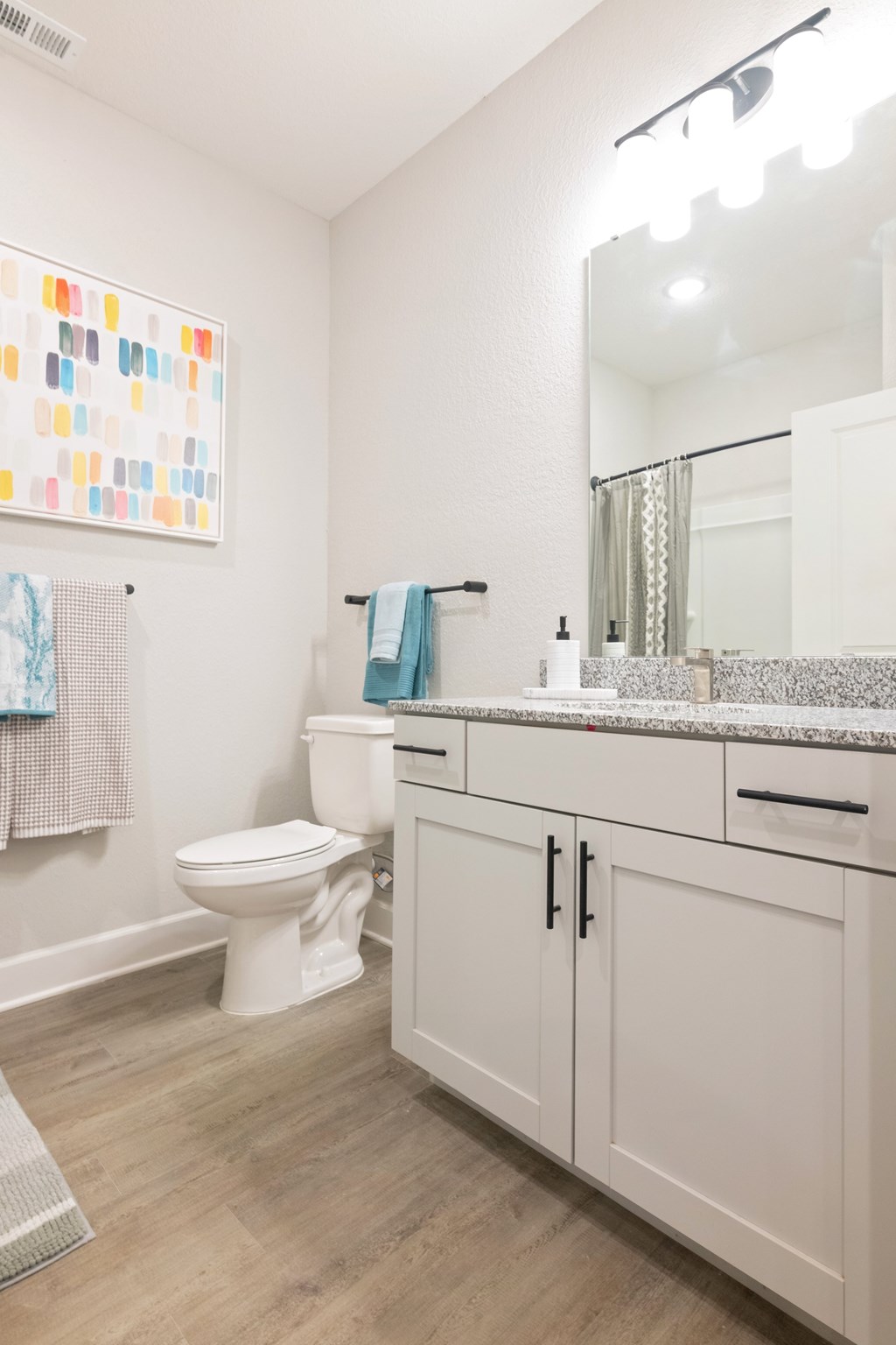 A white toilet sits in a bathroom with a white counter and a mirror.