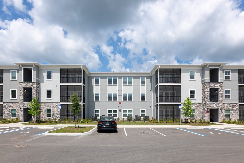 A car is parked in a parking lot in front of a building.