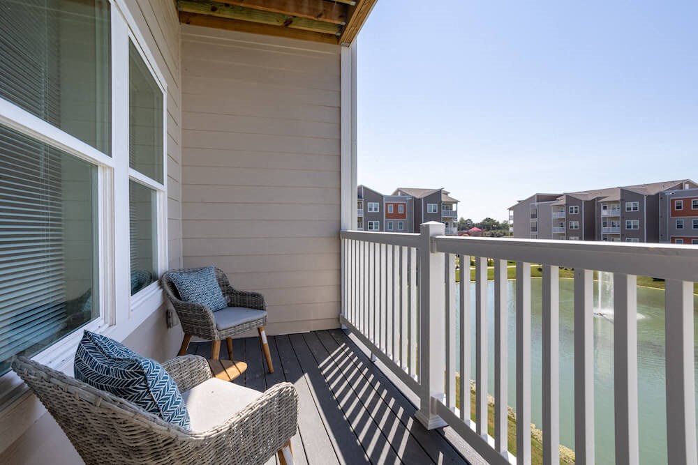 a balcony with two chairs and a view of an apartment complex