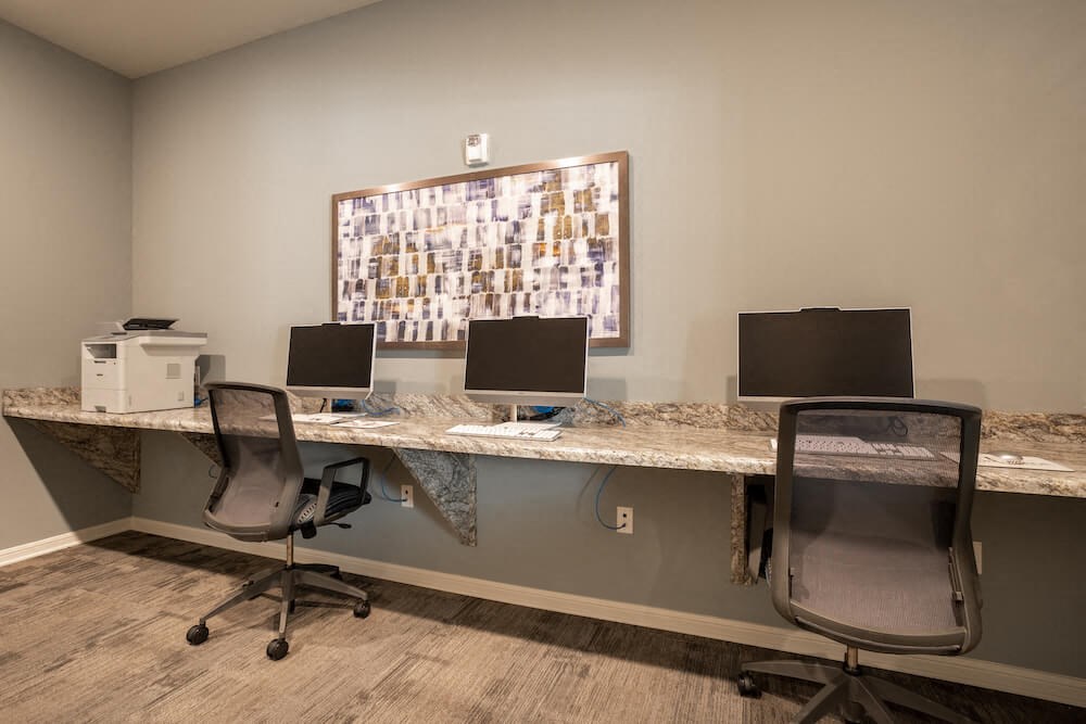 a desk with three computer monitors and a printer on top of it