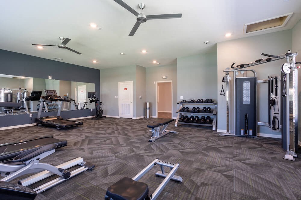 Fitness center with weight machine, dumbbell rack, a treadmill and bench