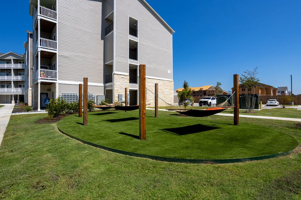 hammock area sitting on green grass with an apartment building in the background