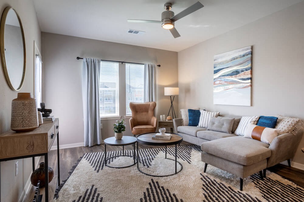 Living room with coffee tables, a couch, and windows