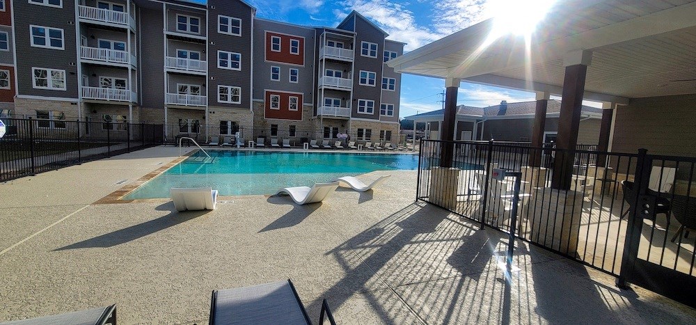 swimming pool with lounge chairs and umbrellas in front of an apartment building