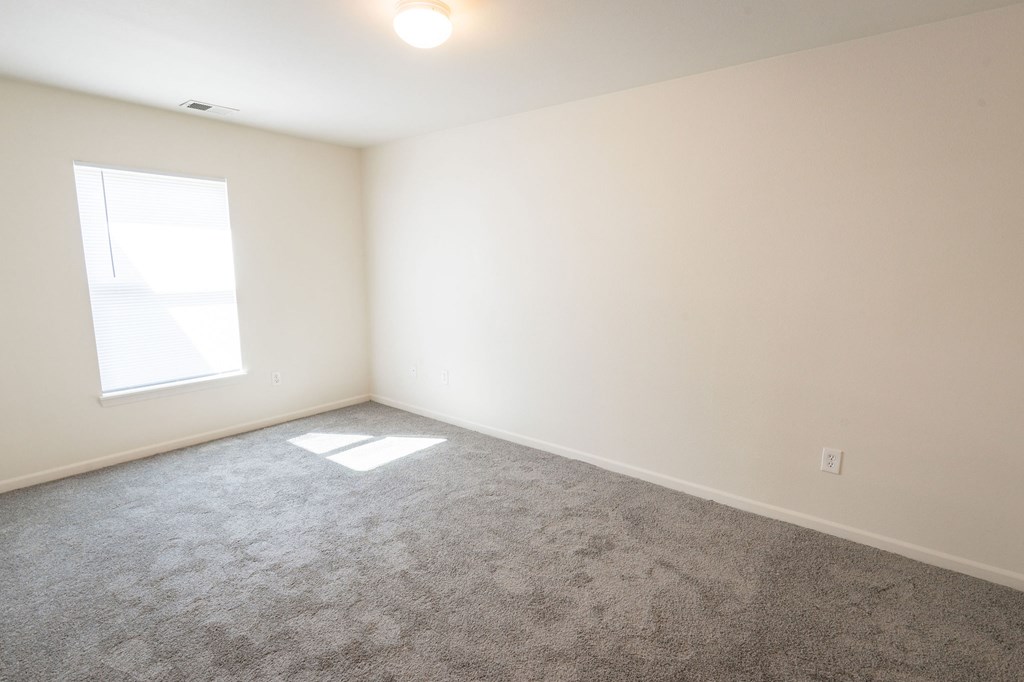 A room with a carpeted floor and a window.