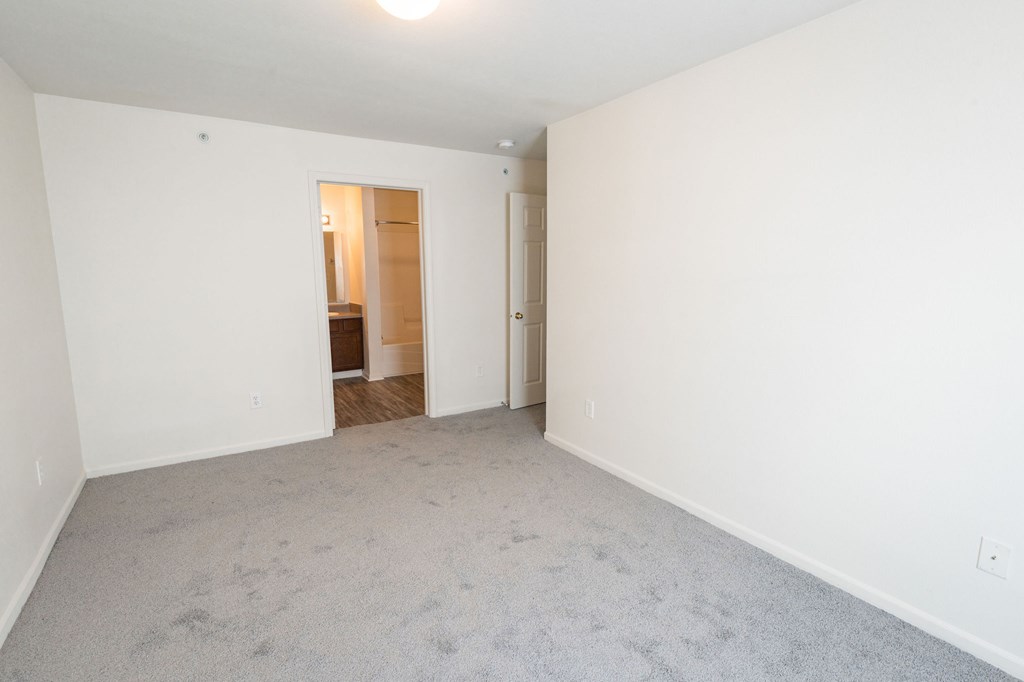 A carpeted room with a doorway leading to another room.