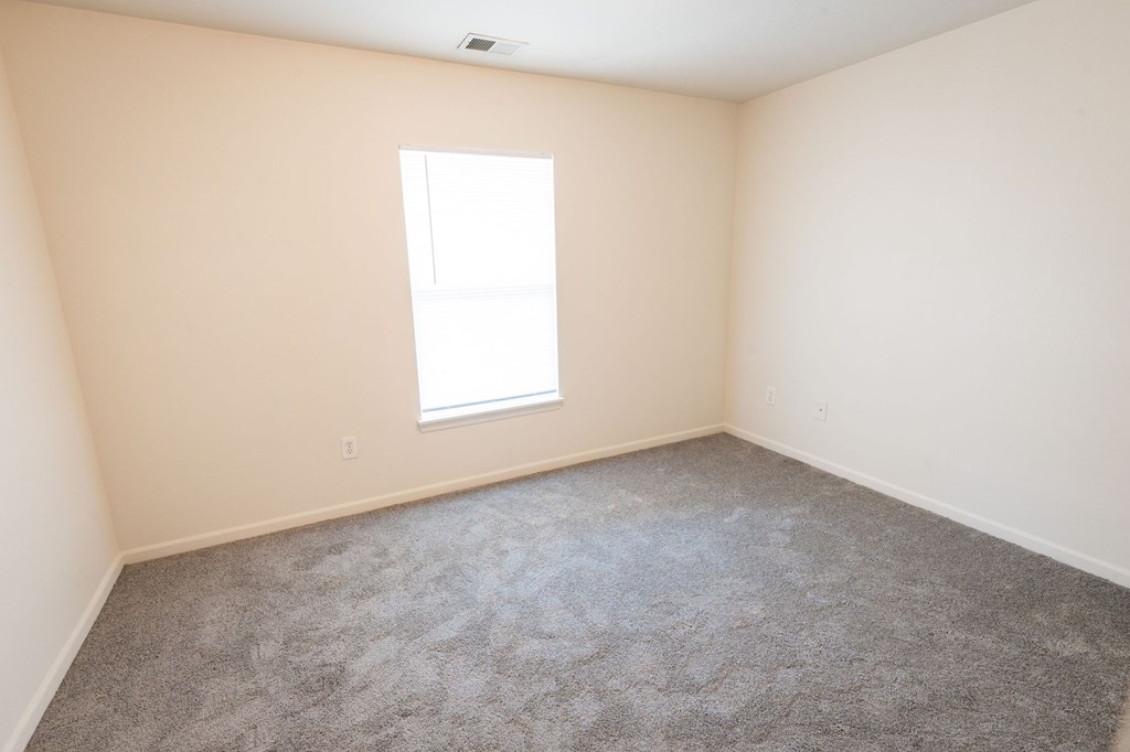A room with a carpeted floor and a window.