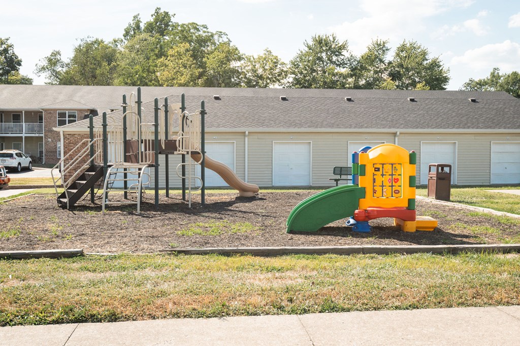 A playground with a yellow and green slide and a red and blue climbing frame.