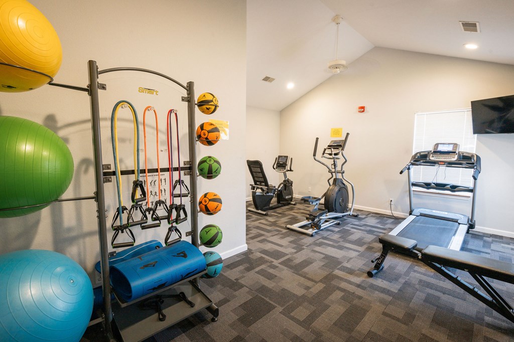 A gym with a variety of equipment including a treadmill, exercise balls, and resistance bands.