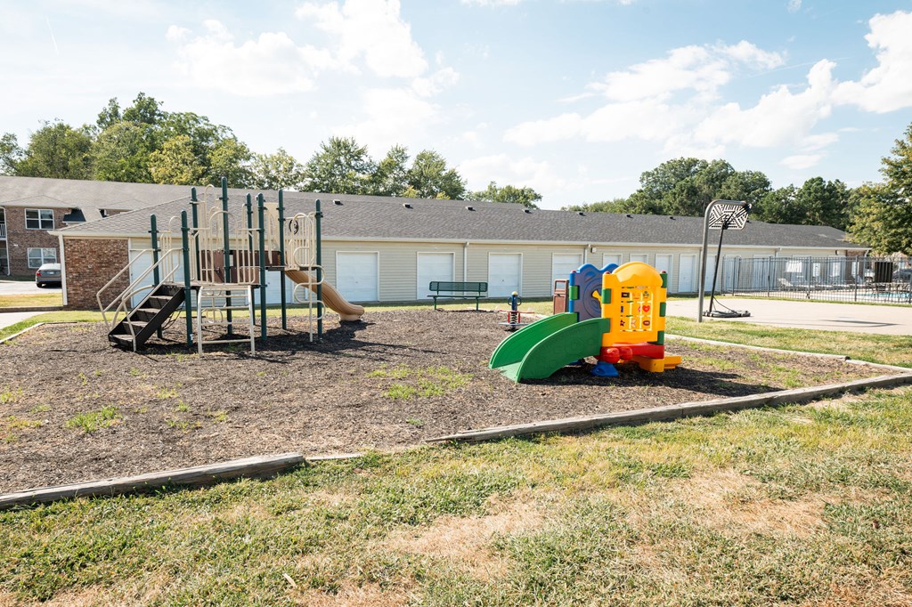 A playground with a yellow and green slide and a brown and green climbing structure.