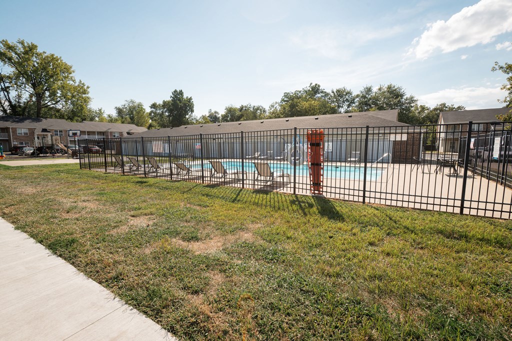 A pool surrounded by a black fence with a red post.