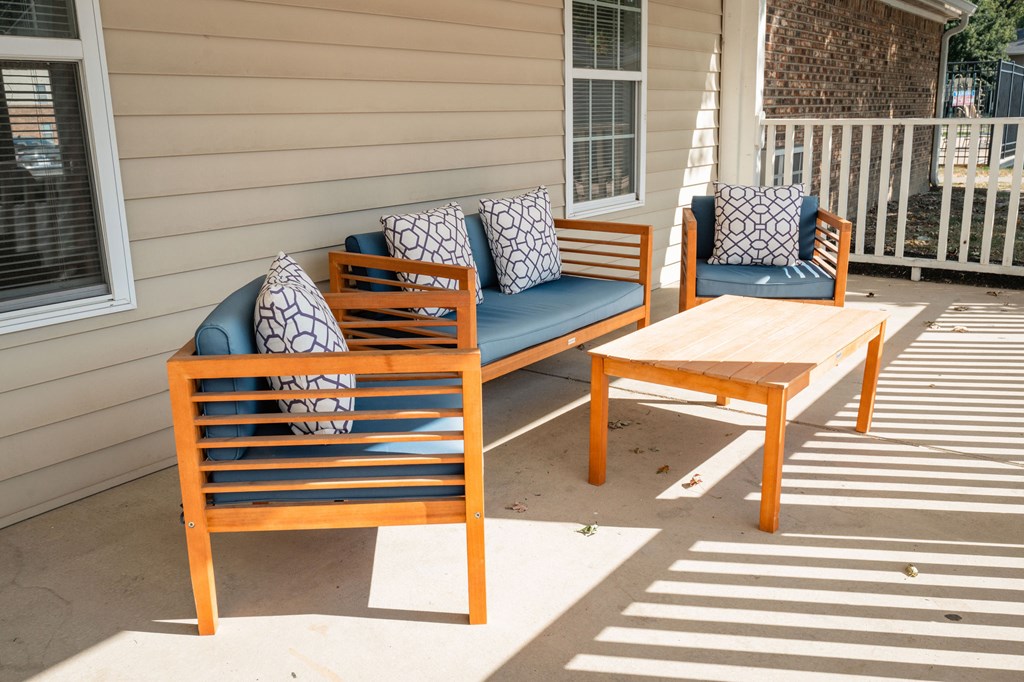 A wooden bench with cushions sits on a patio.
