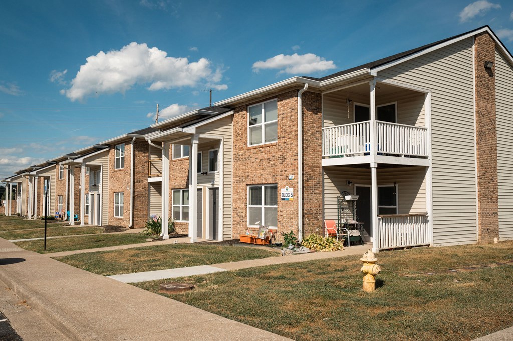 A row of townhouses with a yellow fire hydrant in front of the first one.