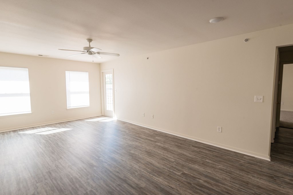 A room with a ceiling fan and two windows.
