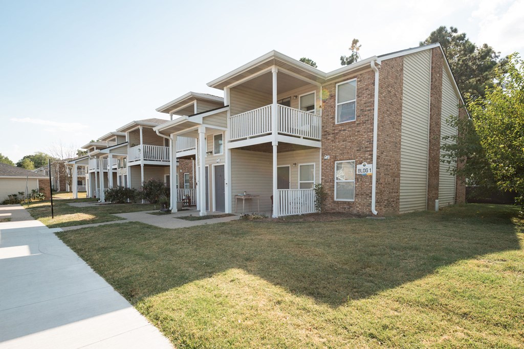 Apartment complex with a white fence and a green lawn.
