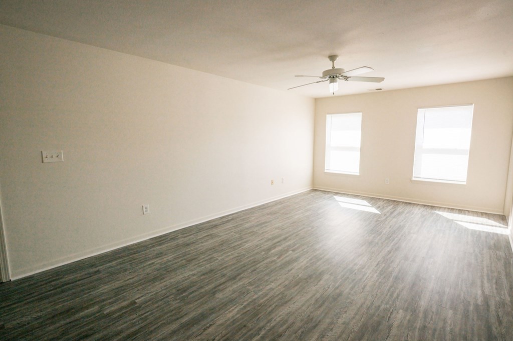 A room with a ceiling fan and two windows.