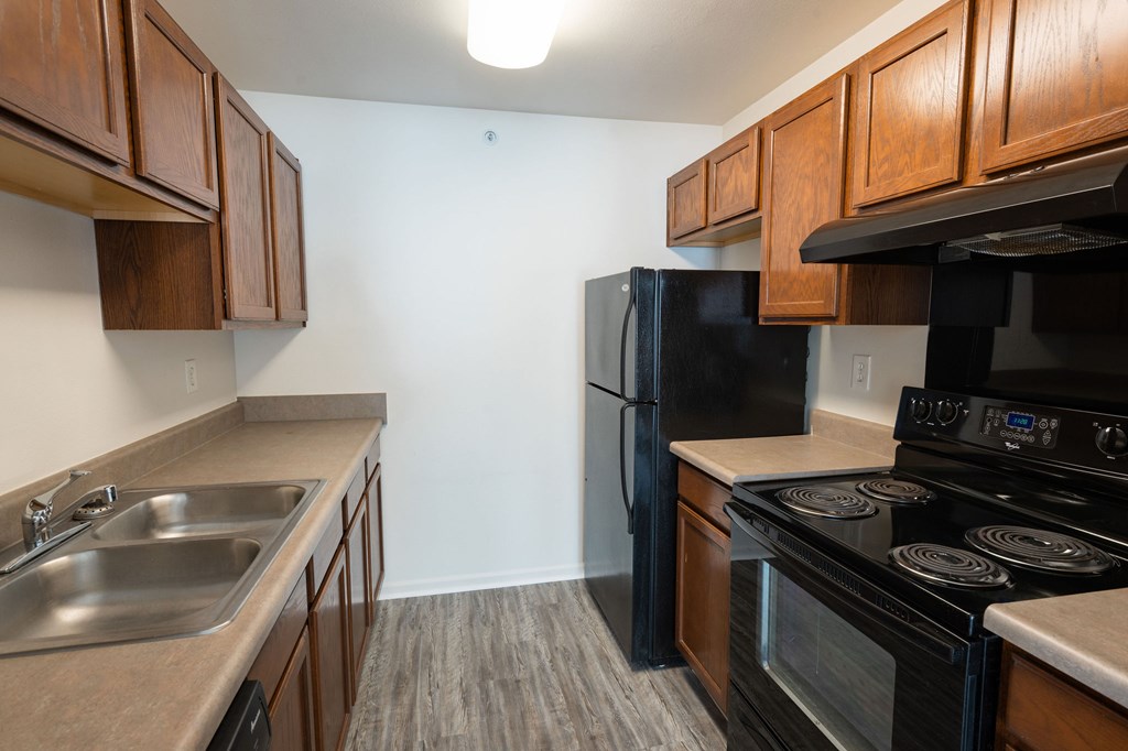 A kitchen with black appliances and wooden cabinets.