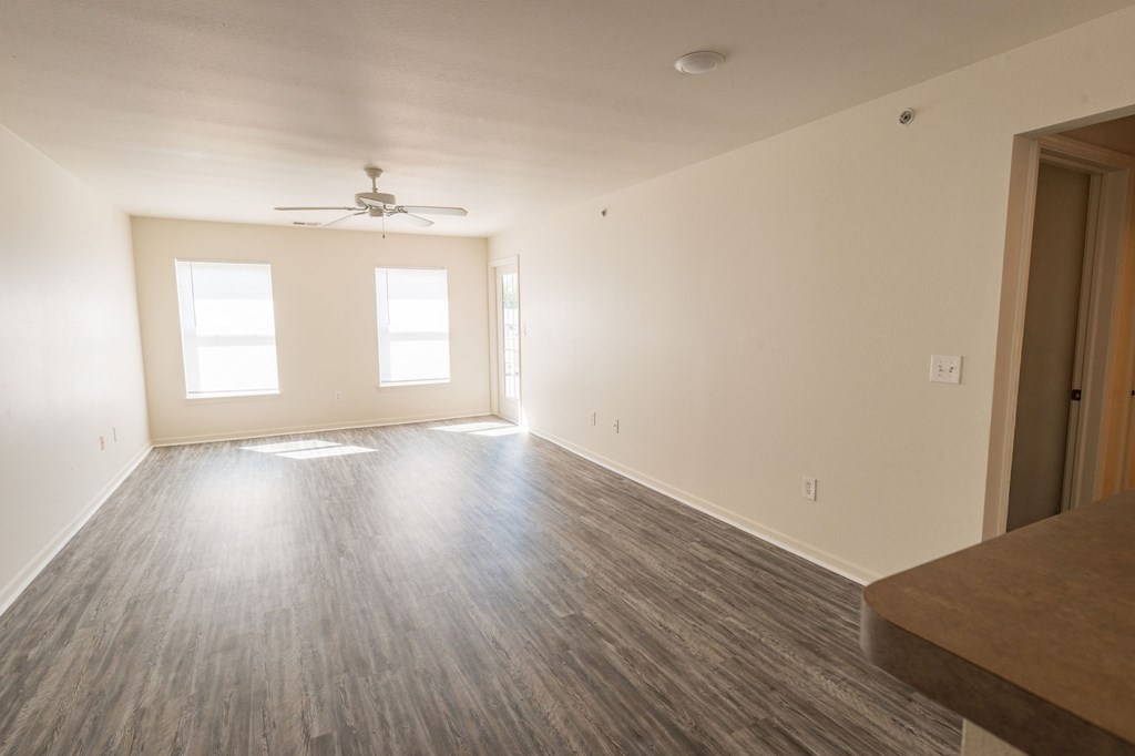 A room with a ceiling fan and two windows.