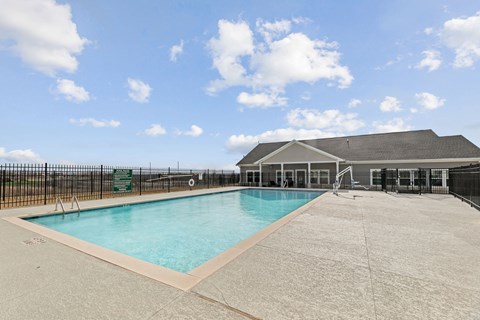 A large outdoor swimming pool with a black fence surrounding it.
