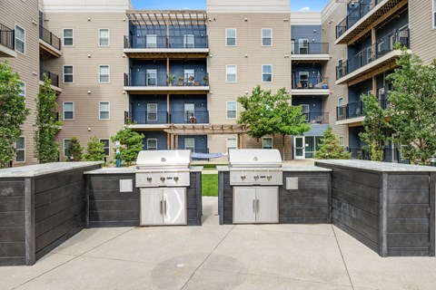 an outdoor kitchen with two stoves in front of an apartment building