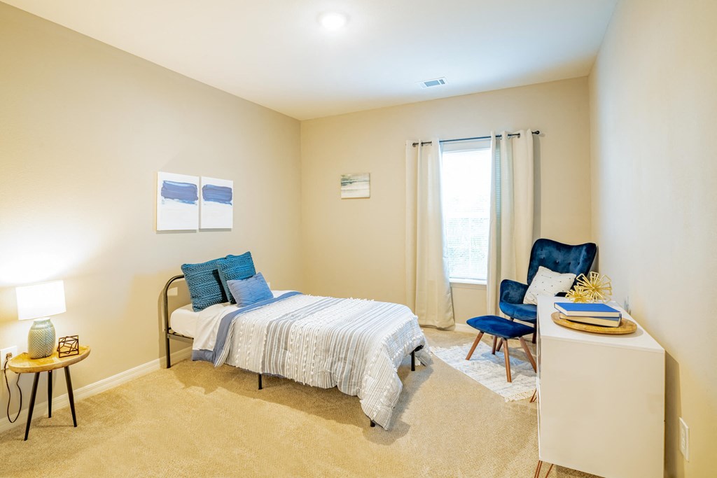 Apartment bedroom with a bed, chair and a window at Trillium apartments in Melbourne fl
