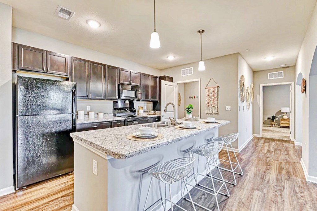 an open kitchen with a bar with stools and a refrigerator at the flats at sundown luxury apartments in north port florida