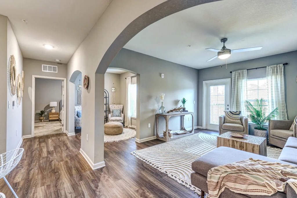 Living room and hallway with a couch, chair, coffee table and two windows at Flats at Sundown apartments in North Port, Fl