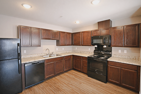 A kitchen with black appliances and wooden cabinets.