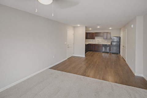 A spacious kitchen with wood floors and white walls.