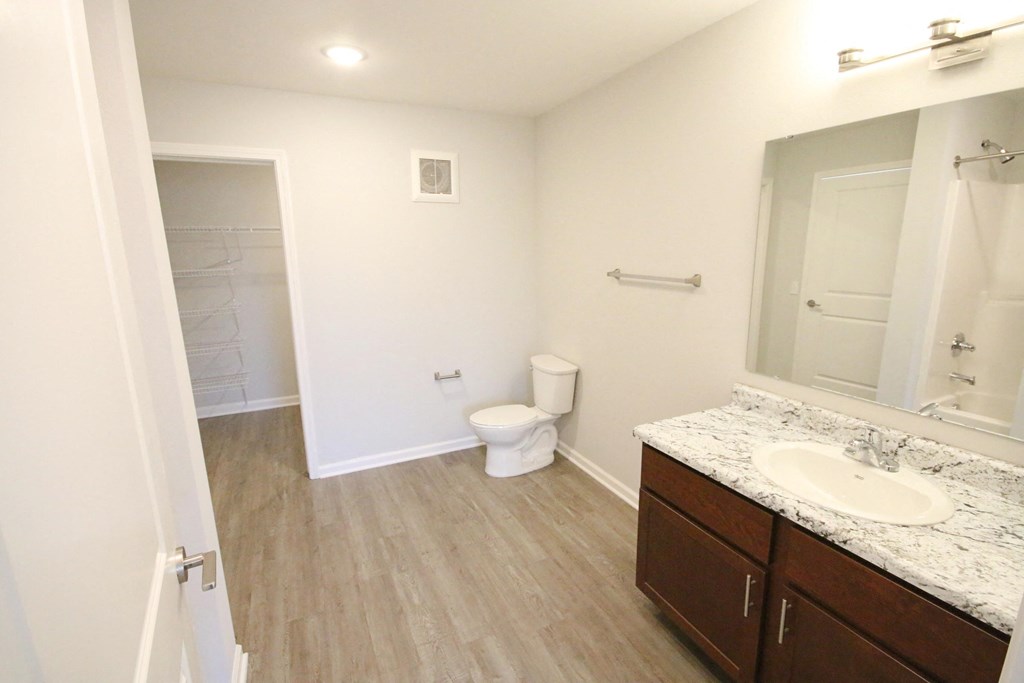 A bathroom with a toilet, sink, and mirror.