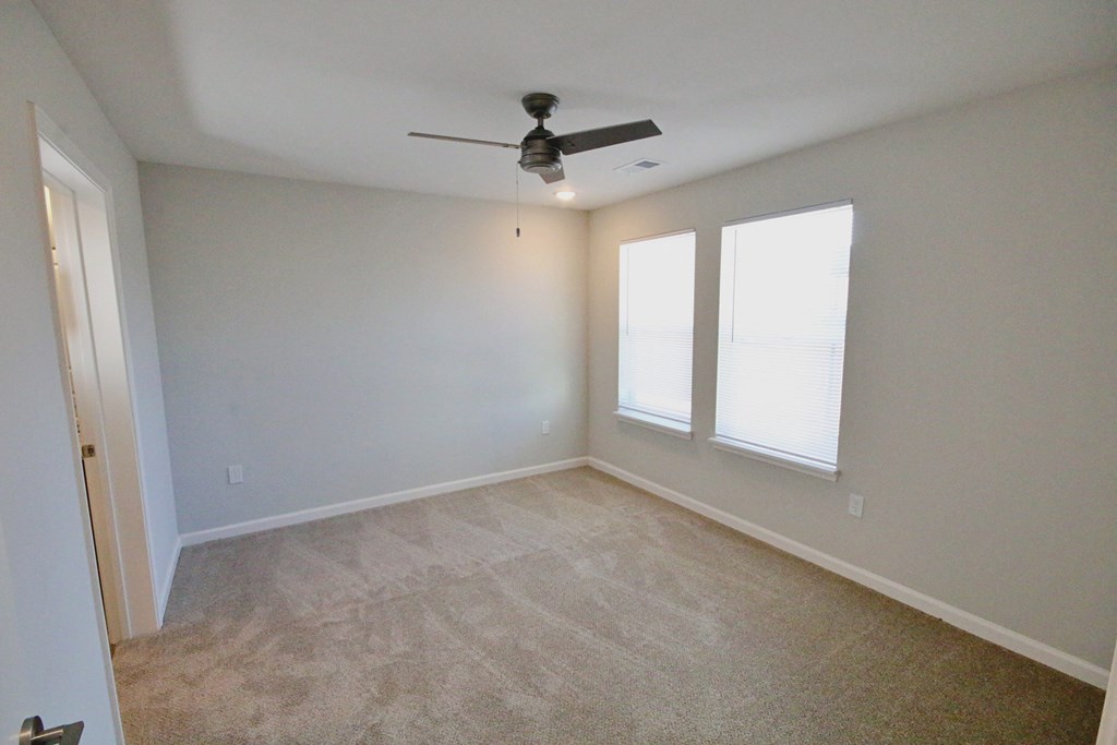 A room with a ceiling fan and two windows