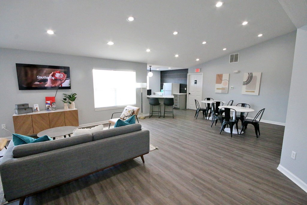 Community living room with a grey couch and a television on the wall at Cobalt apartments in Kokomo, In
