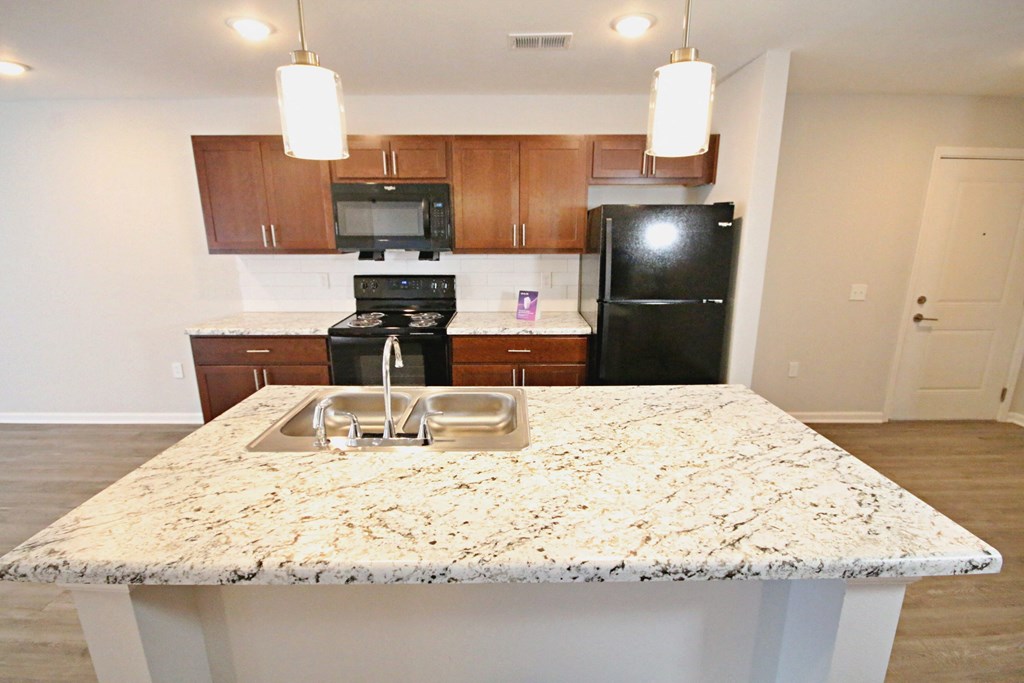 A kitchen with granite countertops and a black refrigerator.