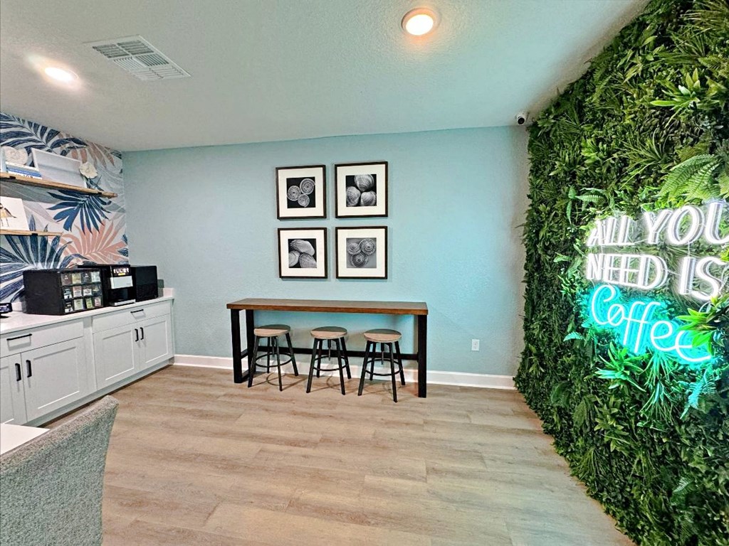 A room with a green wall and a neon sign that says "All you need is coffee".
