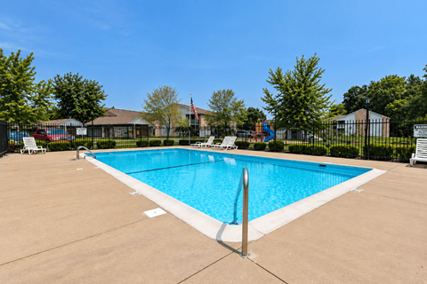 A large swimming pool surrounded by a fence and trees.