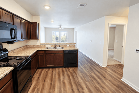 A kitchen with dark wood cabinets and a black stove top oven.