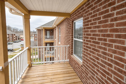 A balcony with a white railing and a brick wall.