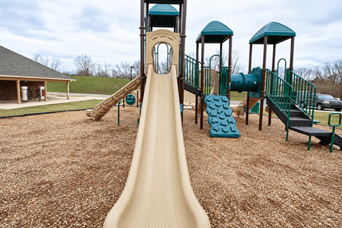 A playground with a slide and a green roofed structure.