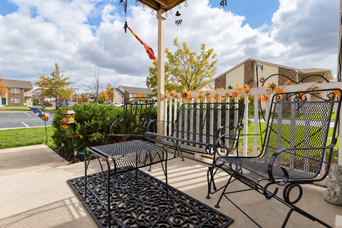 A black metal bench with a black metal table in front of a house.