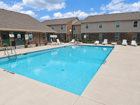 A swimming pool surrounded by lounge chairs and apartment buildings.