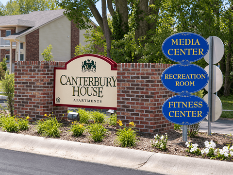A sign for Canterbury House Apartments with three directional signs for Media Center, Recreation Room, and Fitness Center.