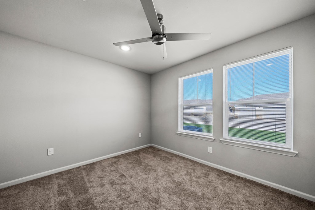 an empty room with two windows and a ceiling fan at legacy square senior apartments in san marcos tx