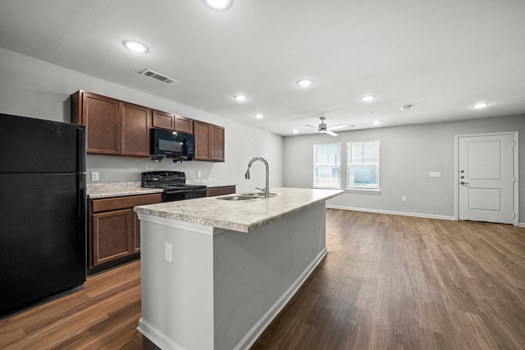 a kitchen with a large island and a black refrigerator at legacy square senior apartments in san marcos tx