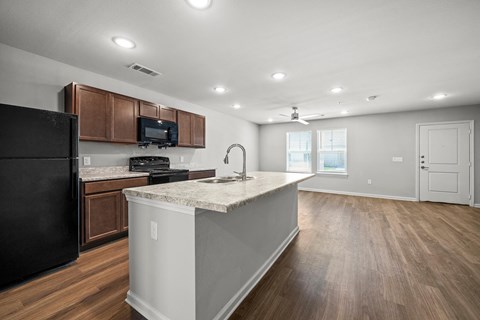 A kitchen with a black refrigerator and a white island.