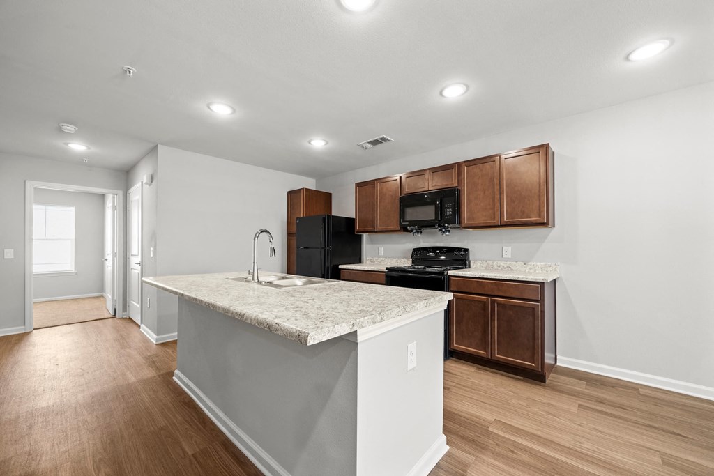a kitchen with a marble counter top and wooden cabinets at legacy square senior apartments in san marcos tx