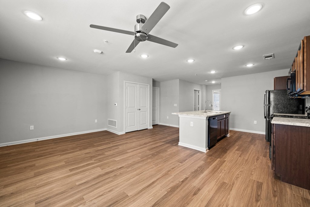 a living room with a kitchen in the background at legacy square senior apartments in san marcos tx