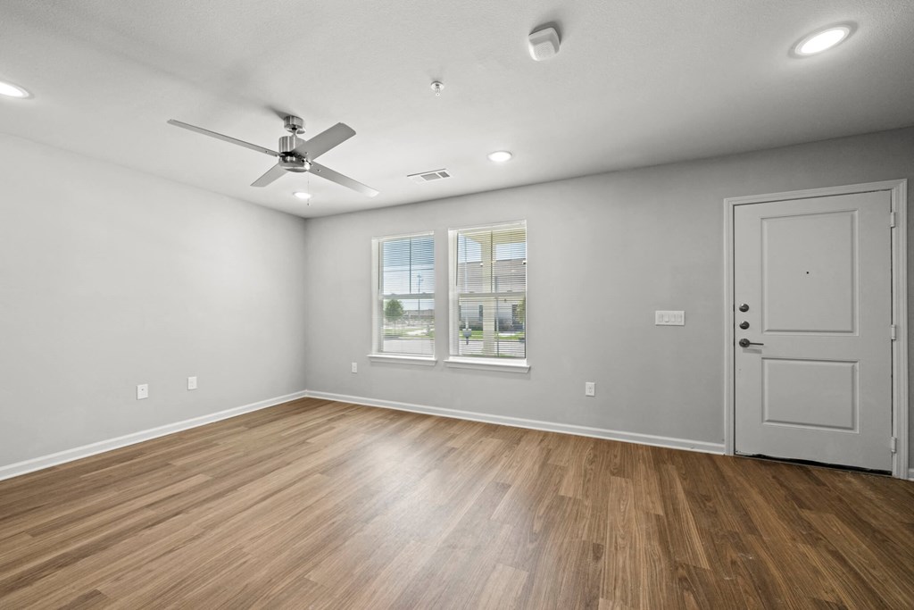 an empty living room with wood floors and a ceiling fan at legacy square senior apartments in san marcos tx